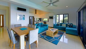 A modern living room with a dining area, a kitchen, and a large window providing natural light. - SPEEDYS SHACK   1770 - panoramic ocean & bay views (SEVENTEEN SEVENTY)