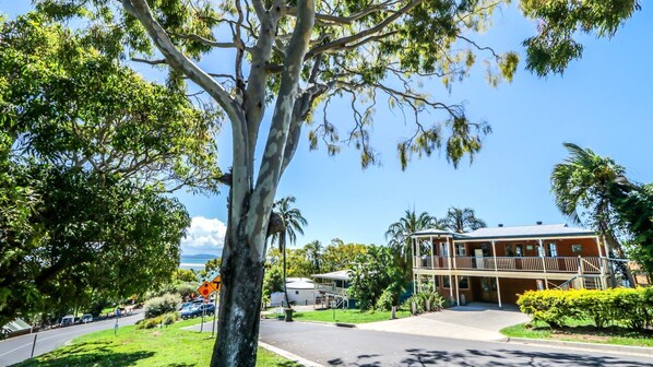 A two-story building with a balcony, surrounded by lush greenery and a clear sky. - ROUND HILL HOUSE 1770 - waterfront views (SEVENTEEN SEVENTY)