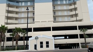 Un immeuble de grande hauteur, sur lequel on peut voir une enseigne bien visible indiquant « TWIN PALMS RESORT, résidence en copropriété », et un parking situé en dessous.