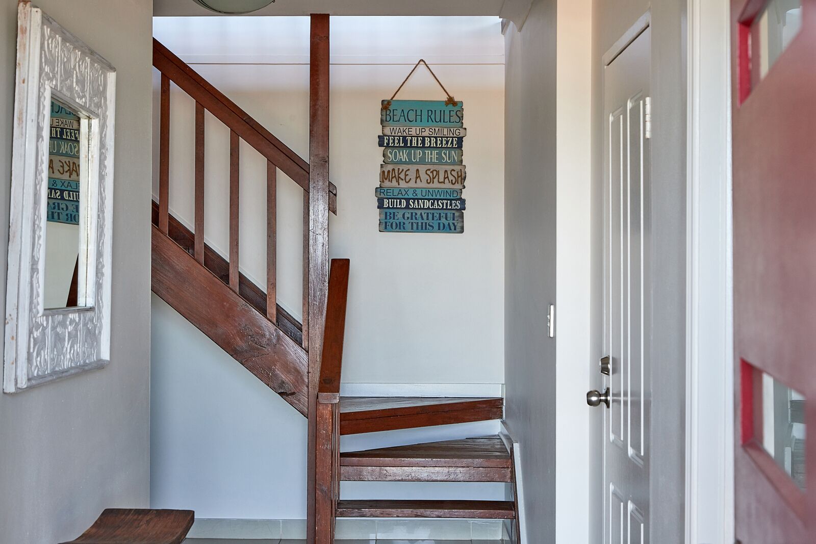 A wooden staircase with a hanging sign listing beach rules.