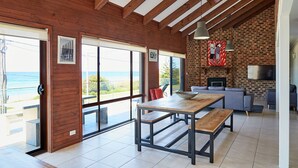A modern kitchen with a brick wall, a large window, and a dining area with a wooden table and benches. - A stone's throw from Mollymook Beach (Mollymook)