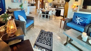 Amplia sala de estar con una mesa de comedor, sofás y una cocina al fondo.