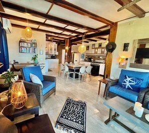 Amplia sala de estar con una mesa de comedor, sofás y una cocina al fondo.