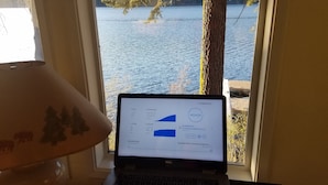 A laptop displaying a speed test result on a window overlooking a body of water.