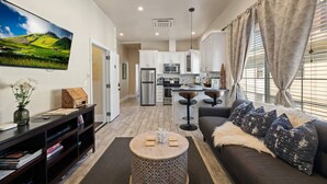 A modern living room with a sofa, coffee table, and a TV mounted on the wall. - Vintage Flat | Mins to Golden 1 Center, Capitol (Sacramento)