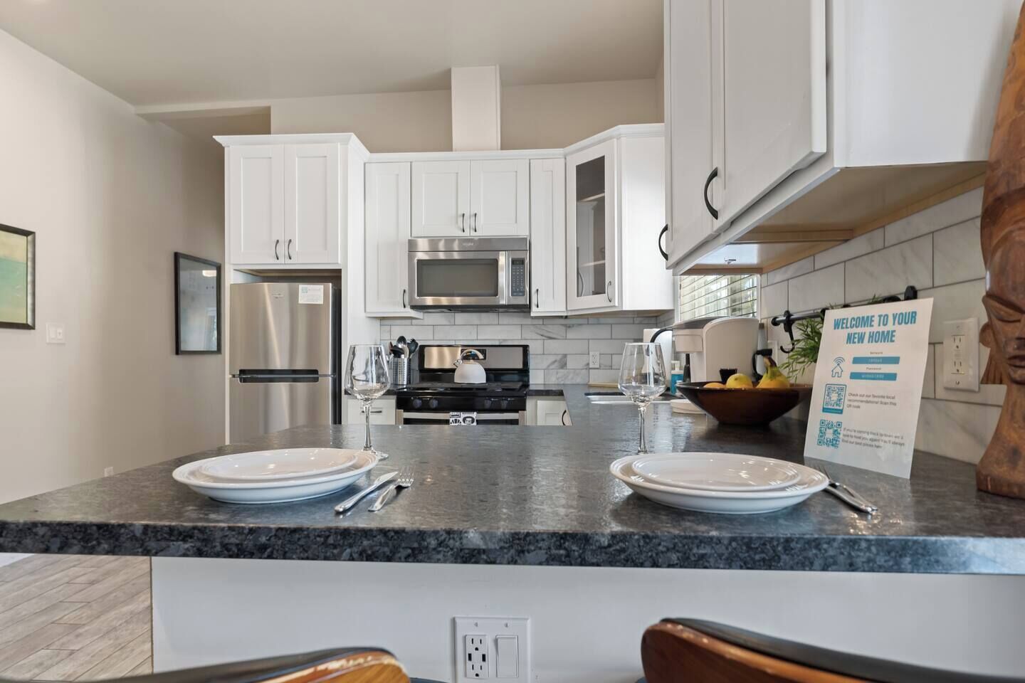 A modern kitchen with white cabinets, stainless steel appliances, and a granite countertop.