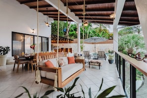 Un grand espace extérieur aménagé avec des sièges, une balançoire, une table à manger et des chaises.