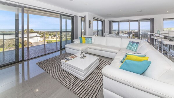 Relax in this spacious living room with a large sofa, expansive views of the coastline, and a stylish coffee table.
