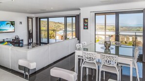 Relax in a spacious living area with a large dining table, comfortable seating, and a TV for entertainment.
