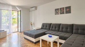 A modern living room with a sectional sofa, a small white table, and a sliding glass door leading to an outdoor area. - Holiday apartment in village Valbandon, 1km from the beach (Valbandon, Fažana)