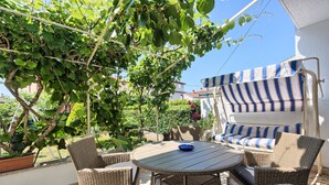 A patio with wicker furniture, a striped awning, and a potted plant. - Holiday apartment in village Valbandon, 1km from the beach (Valbandon, Fažana)