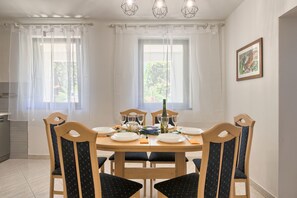 A dining area with a round table, four chairs, and a chandelier.