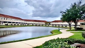 A large building with a central courtyard, a pond, and a tree.
