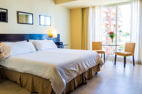 One of our pair of vacation studios in Buenos Aires, Argentina, with its king bed, dining table, and French-balcony window.