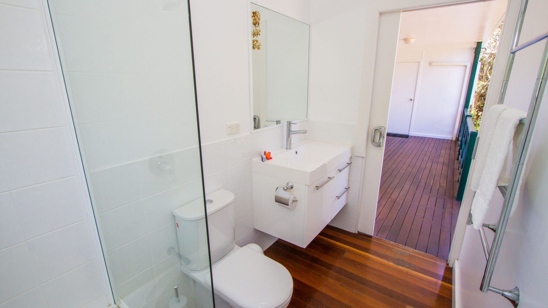 A modern bathroom with a glass shower enclosure, a white toilet, and a vanity with a mirror.