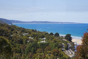 A coastal landscape with dense greenery, a beach, and a road leading to a junction. - Ben-My-Chree (Lorne)