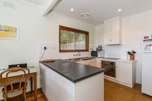 A compact kitchen with a central island, a microwave, an oven, and a sink. - Ben-My-Chree (Lorne)