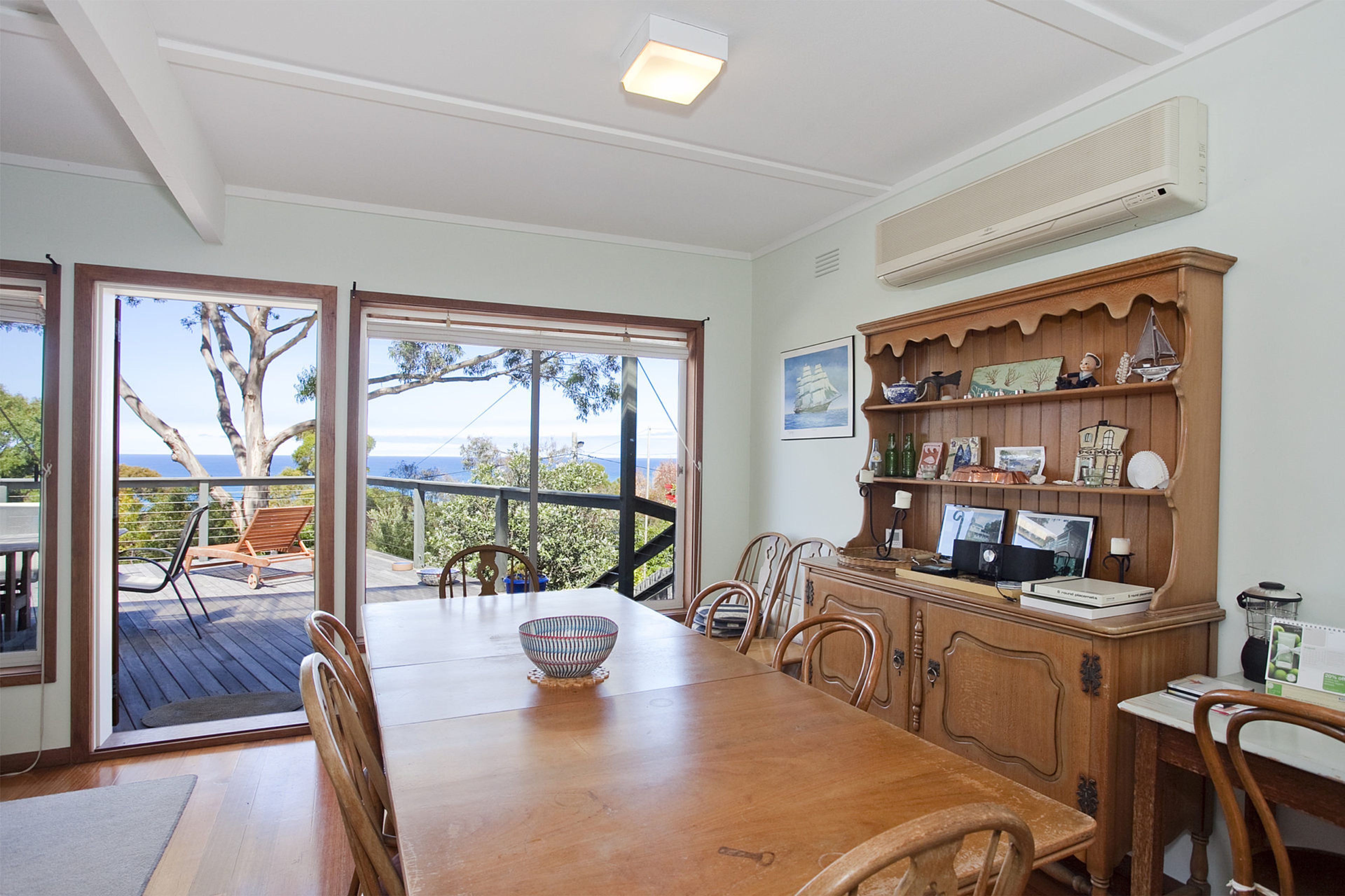 A dining area with a wooden table, chairs, and a view through glass doors to the outdoors.