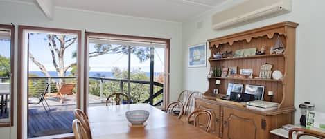 A dining area with a wooden table, chairs, and a view through glass doors to the outdoors.