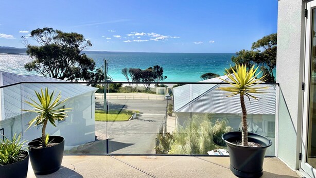 Ein Balkon mit Blick auf das Meer, Kübelpflanzen und einem klaren Himmel.