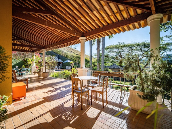 Une terrasse extérieure avec des meubles en bois, un sol carrelé et une vue sur une colline.