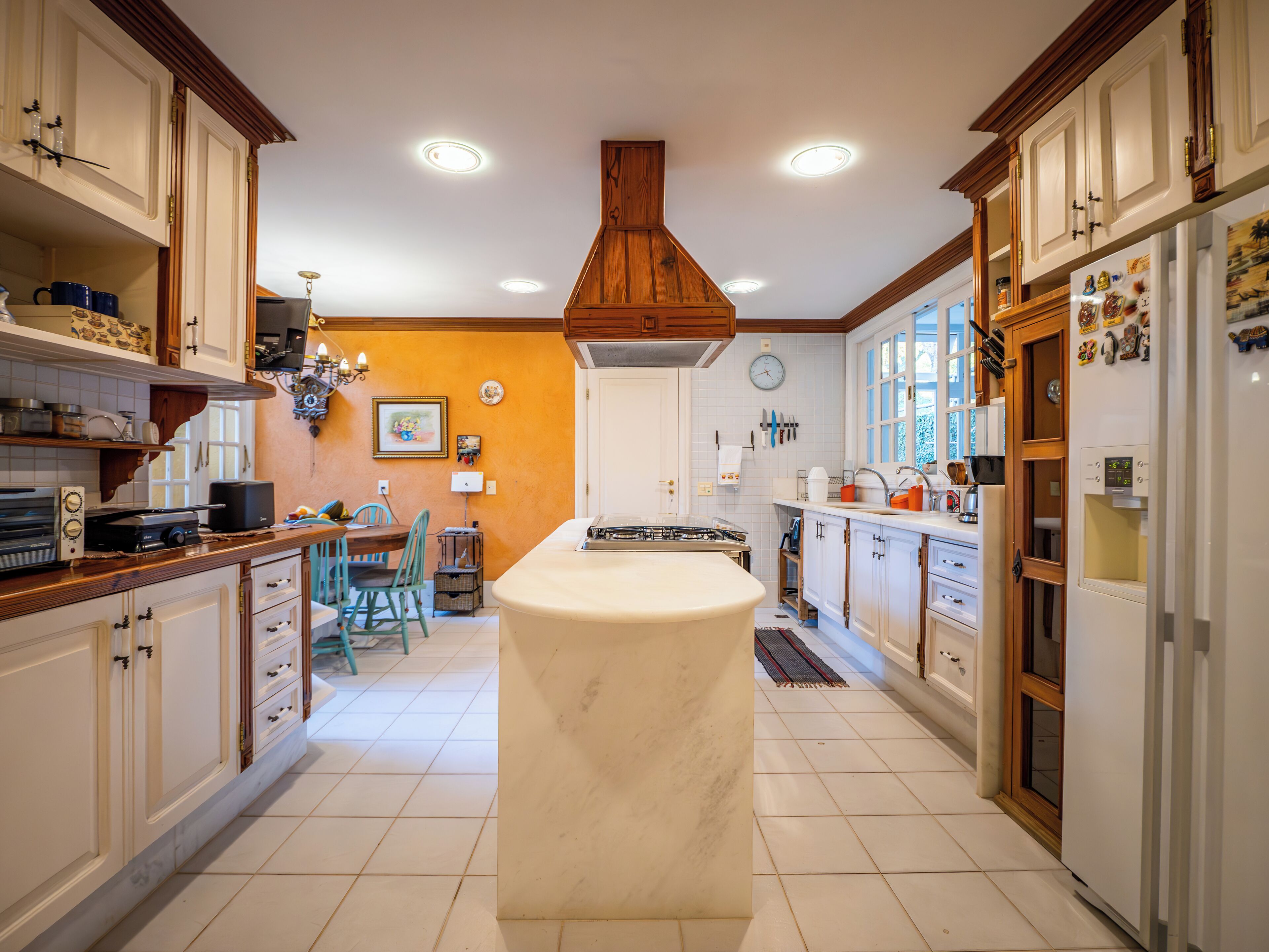 Een keuken met houten kastjes, een centraal eiland en een klok aan de muur.