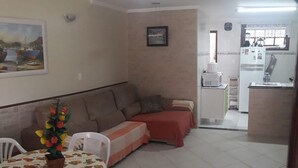 A dining area with a table and chairs, a sofa, and a kitchen area with a refrigerator and microwave. - EXCELLENT DUPLEX HOUSE NEARBY PERÓ AND CONCHAS BEACH!!! (Peró)