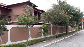 A cobblestone street lined with traditional houses, a white wall with brown panels, and a tree with orange flowers. - EXCELLENT DUPLEX HOUSE NEARBY PERÓ AND CONCHAS BEACH!!! (Peró)