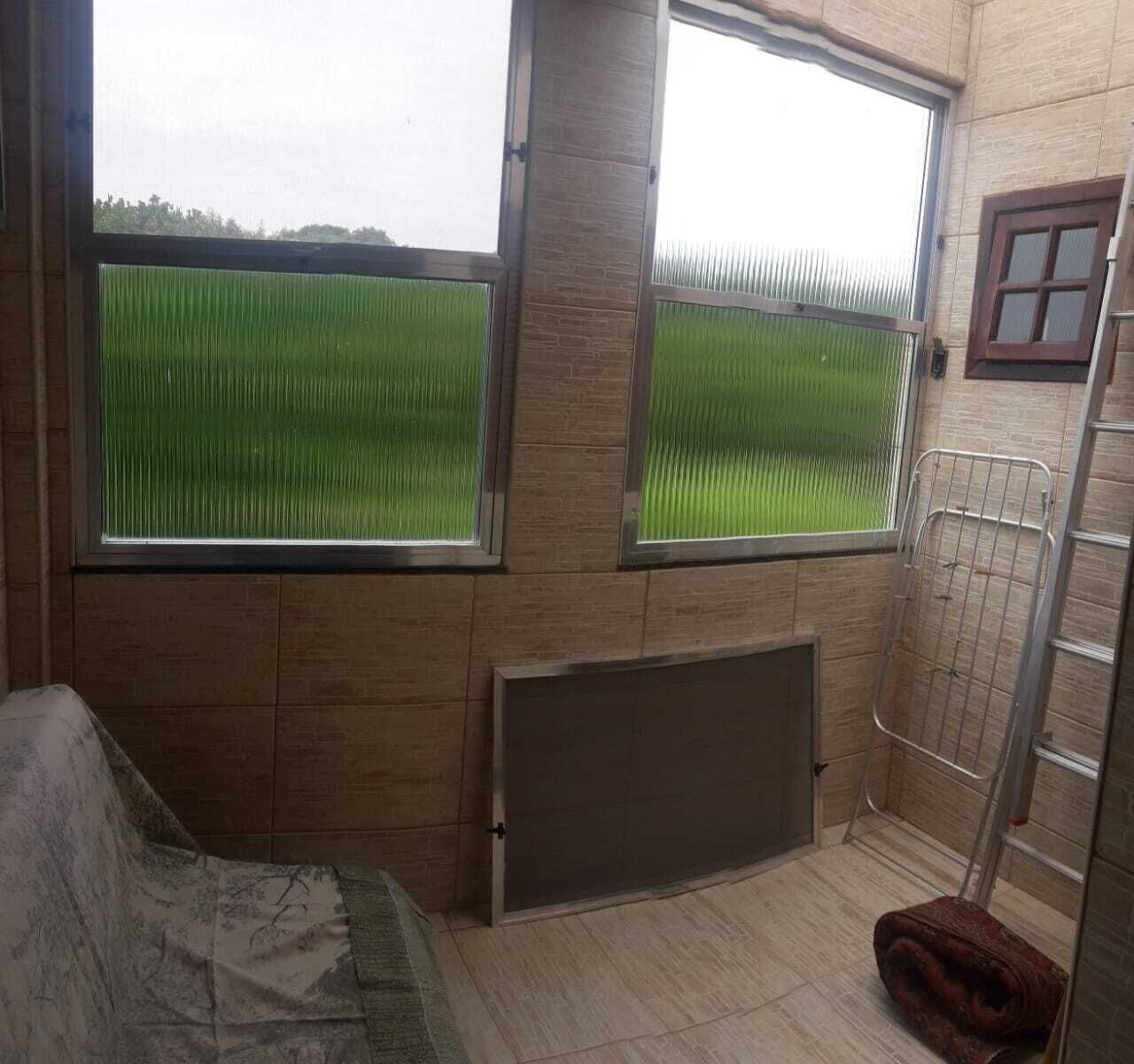 Une pièce dotée de grandes fenêtres, d’un radiateur, d’une étagère en métal et d’un canapé à motifs.