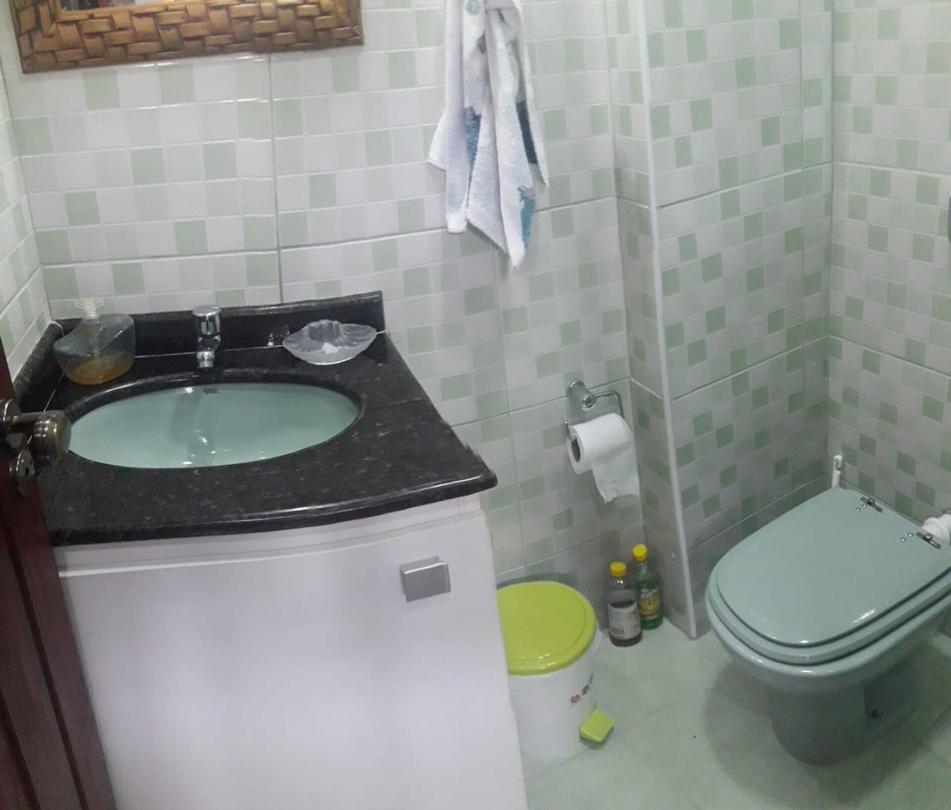A bathroom with a sink, toilet, and a small trash bin.