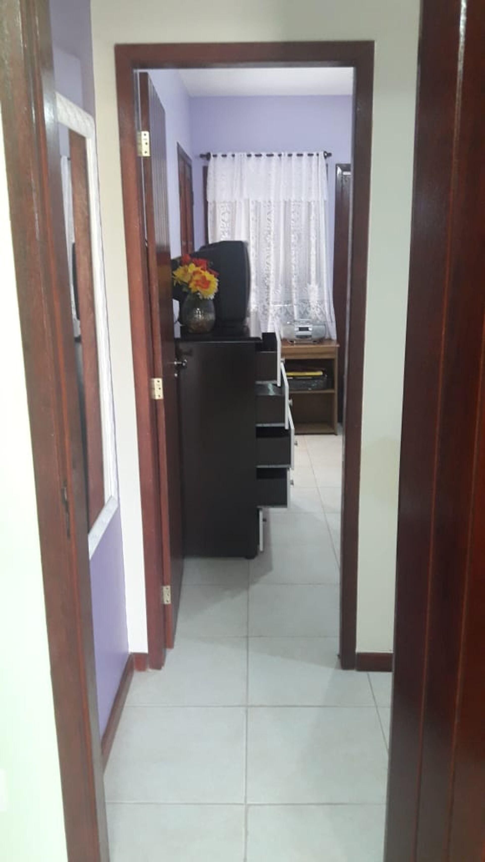 A hallway with a black cabinet and a small table with a vase of flowers.