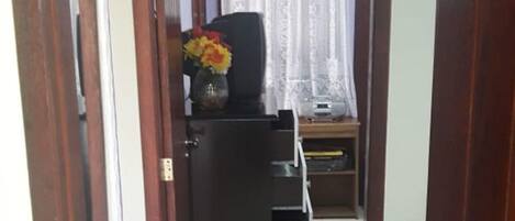 A hallway with a black cabinet and a small table with a vase of flowers.