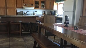 A kitchen with wooden cabinets, a dining table with benches, a refrigerator, and a coffee maker. - Popular Vacation Rental At The Grand Canyon, Make yourselves at Home! (Williams)