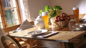 Ein Holztisch mit einer weißen Krug, einem Bierglas, Brezeln und einem Brotkorb.
