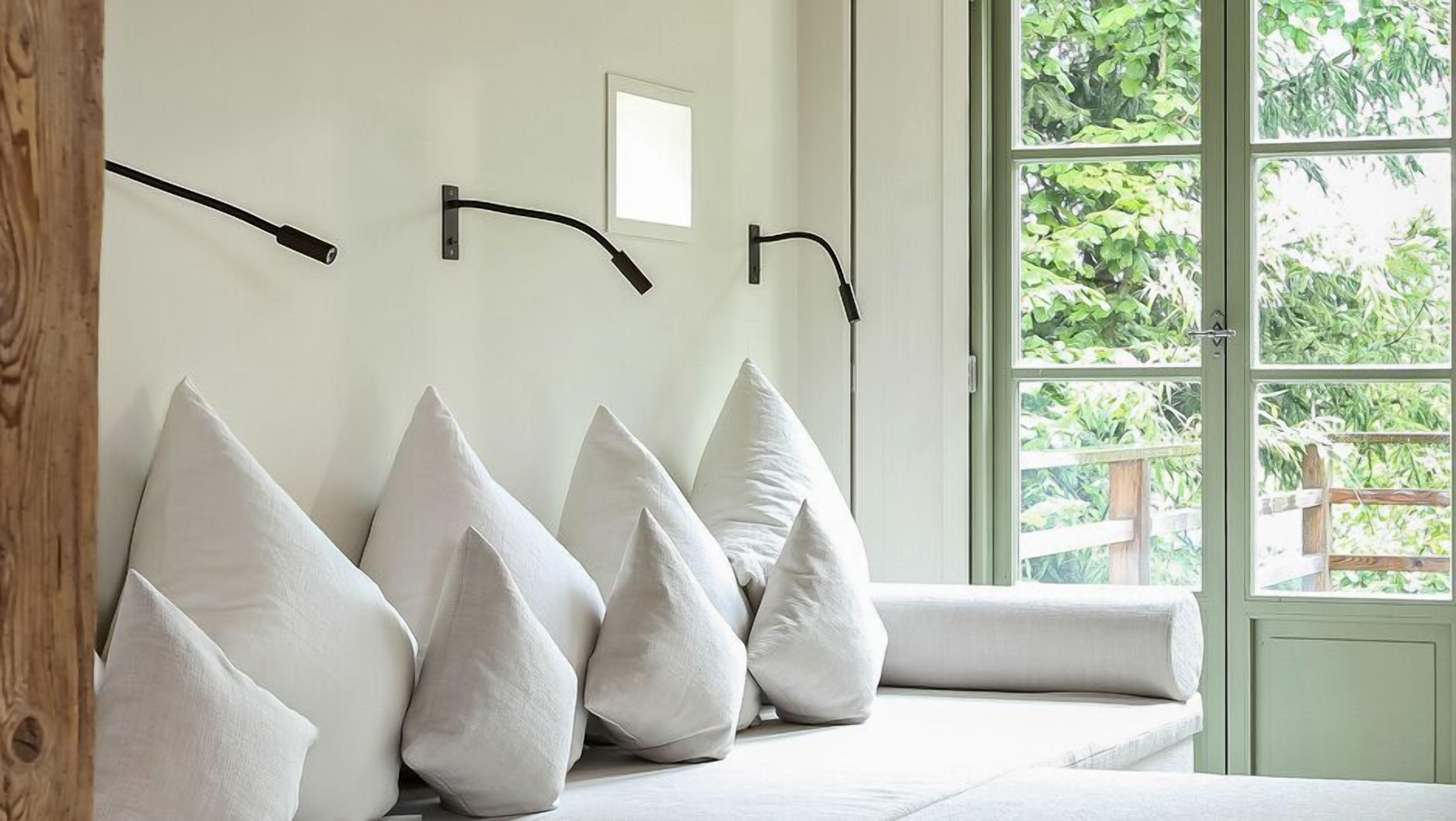 A room with a large window, a white wall, and a wooden beam.
