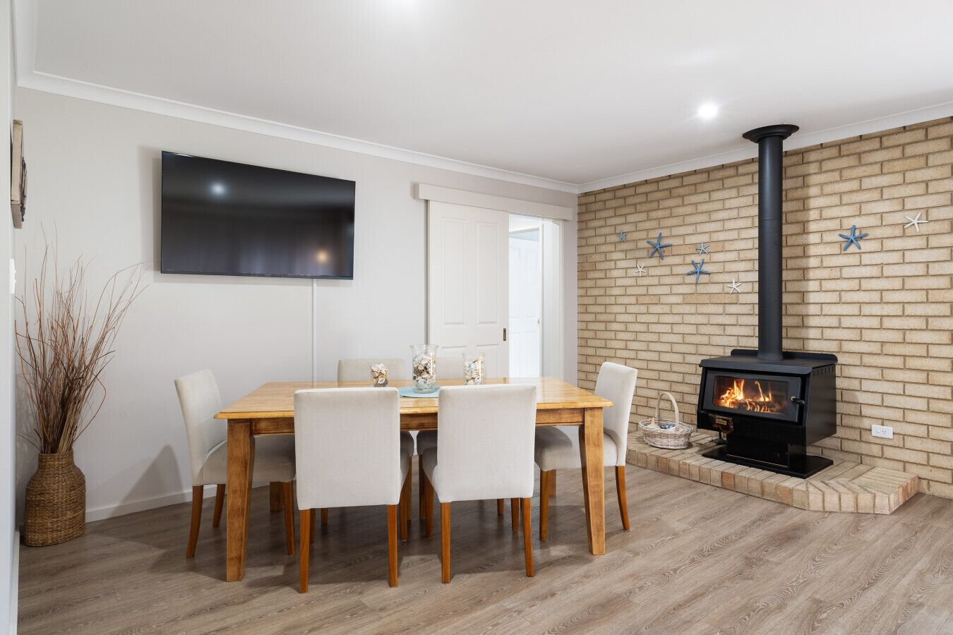Un comedor con pared de ladrillo, chimenea y televisor de pantalla plana.