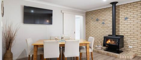 Un comedor con pared de ladrillo, chimenea y televisor de pantalla plana.