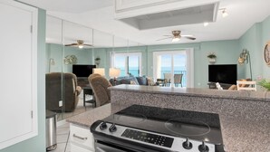 A kitchen with a granite countertop, a stove, and a dining area with a table and chairs.