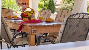 Una mesa de madera con sillas, una cesta de fruta y vasos de jugo de naranja.