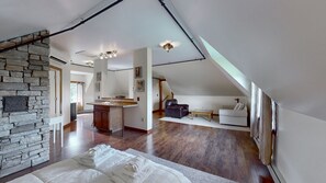 Een ruime loft met een stenen openhaard, een keukenhoek en een woonruimte met een bank en een salontafel.