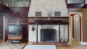 A living room with a fireplace, a television, and a patterned wall. - Rent an entire lake-view estate in the heart of wine country!   (Hammondsport)