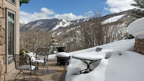 A patio with snow-covered furniture, a stone wall, and a view of snow-capped mountains. - Panoramic View, Great Outdoor Space, Private Elevator, Monthly Rentals Available (Vail)