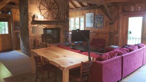 A rustic cabin interior with a stone fireplace, wooden furniture, and a large window. - Stunning view from this secluded mountain gettaway (West Alton)