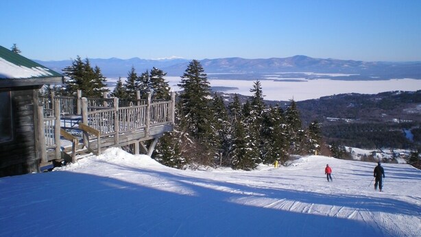 A snow-covered ski slope with a wooden viewing platform and a building with a green roof. - Stunning view from this secluded mountain gettaway (West Alton)