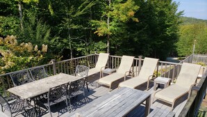 A wooden deck with metal furniture, including tables and chairs, surrounded by trees. - Stunning view from this secluded mountain gettaway (West Alton)