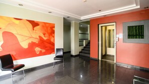 Eine moderne Lobby mit einer großen abstrakten Wandmalerei, einer Treppe und einem Empfangstresen.