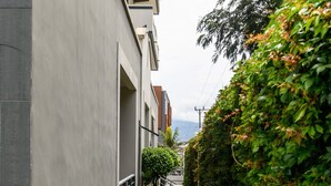 Ein schmaler Ziegelweg, der von einer niedrigen Hecke und einem modernen Gebäude mit flacher Fassade gesäumt wird.