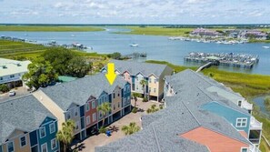 A coastal residential area with a marina, houses with sloped roofs, and a dock extending into the water.