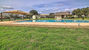 Un jardin avec une piscine, un patio couvert et une maison en arrière-plan.
