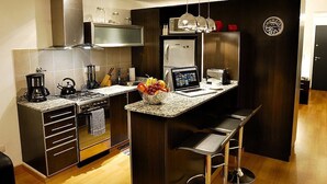 A modern kitchen with stainless steel appliances, a built-in oven, and a central island with bar stools.